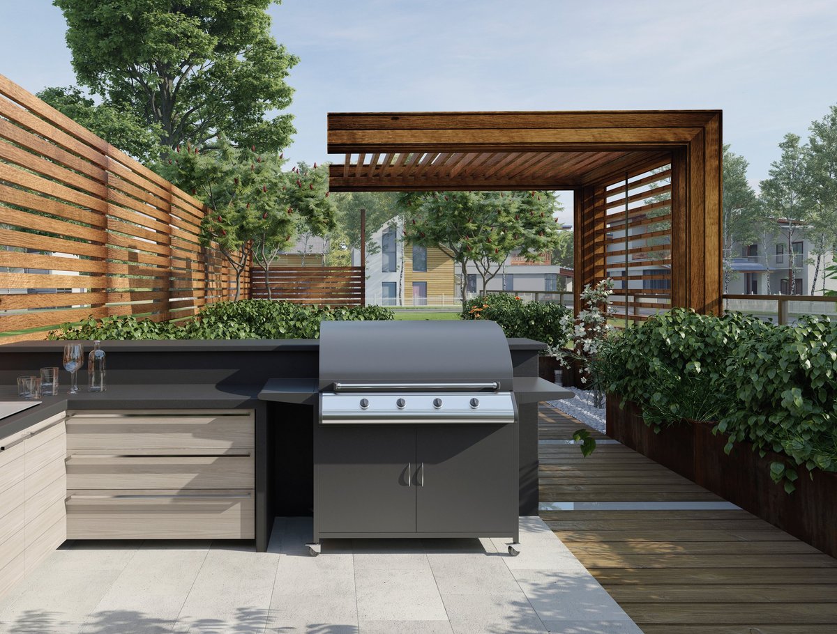 Modern outdoor kitchen on a wooden patio with gas grill and dark countertops