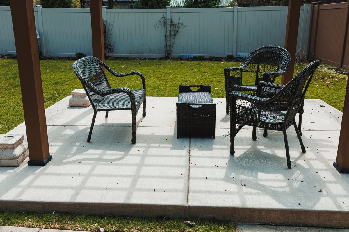 Backyard seating area with two chairs and a small table on concrete