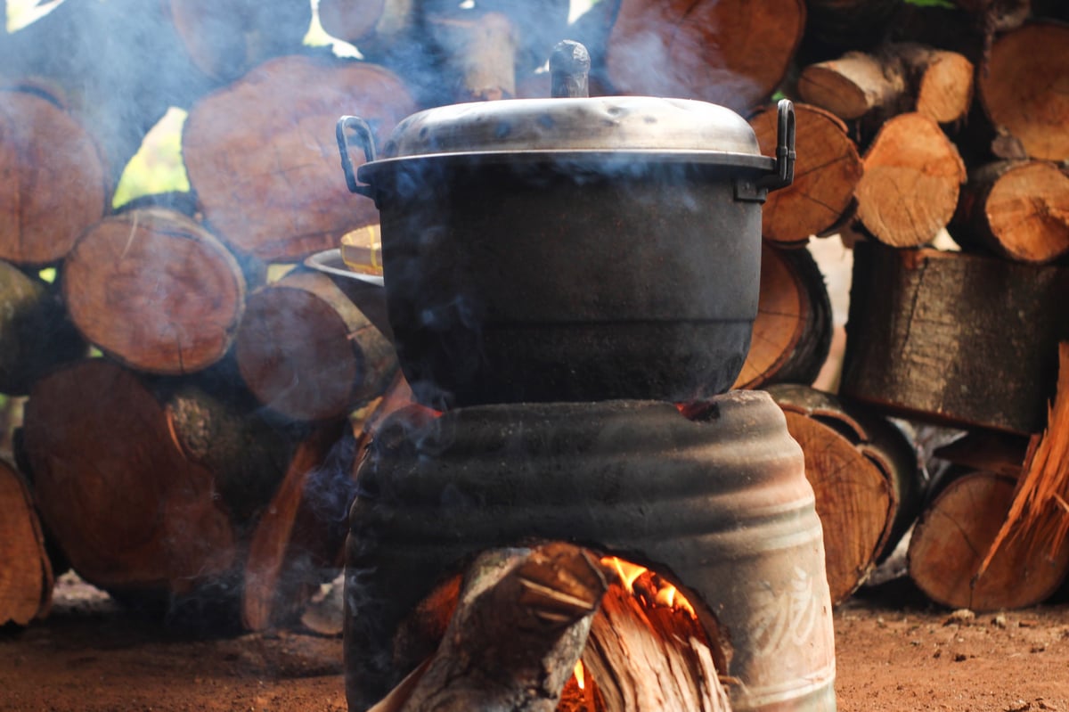 Large pot on a traditional clay stove with firewood stacked behind